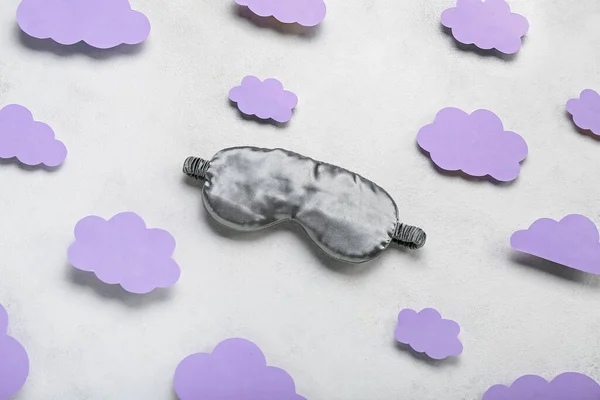 Composition with sleeping mask and paper clouds on light background. World Sleep Day concept