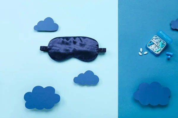 Composition with sleeping mask, pills and paper clouds on color background. World Sleep Day concept