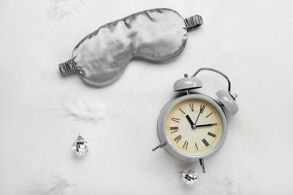 Composition with sleeping mask, alarm clock, feathers and Christmas balls on light background. World Sleep Day concept