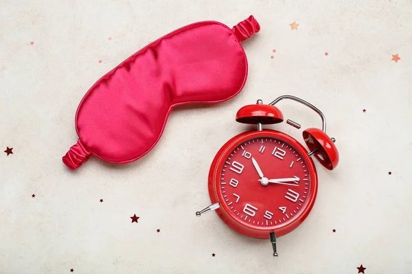 Sleeping mask and alarm clock on light background. World Sleep Day concept