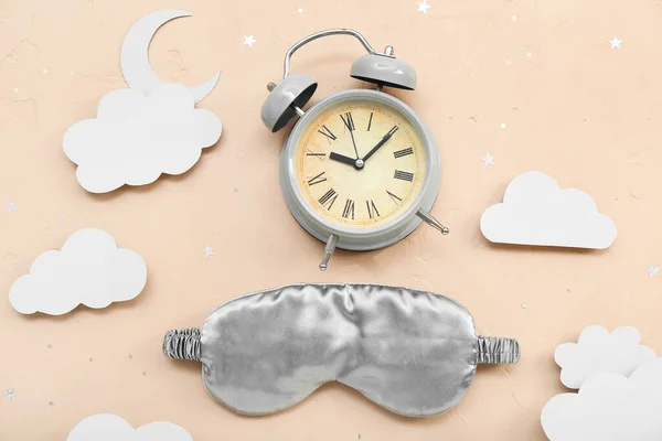 Composition with alarm clock, sleeping mask and paper decor on color background. World Sleep Day concept