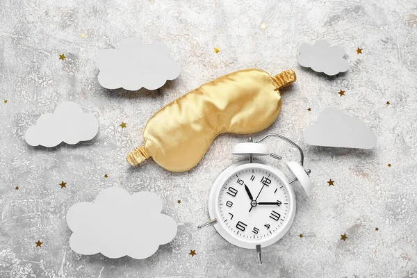 Composition with alarm clock, sleeping mask and paper clouds on grunge background. World Sleep Day concept