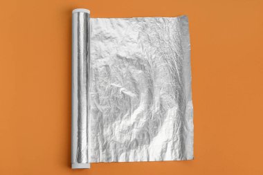 Roll of aluminium foil on color background
