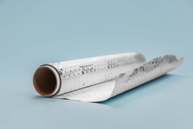 Roll of aluminium foil on color background