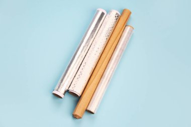 Rolls of aluminium foil, baking paper and food film on color background