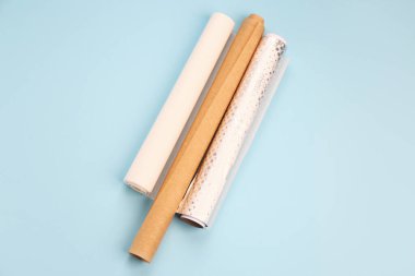 Rolls of aluminium foil and baking paper on blue background