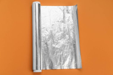 Aluminium foil roll on orange background
