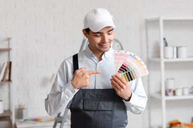 Male painter pointing at color palettes in room