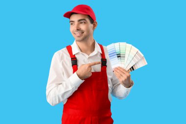 Male painter pointing at color palettes on blue background