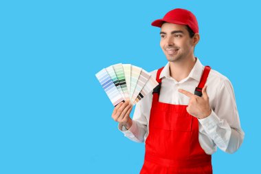 Male painter pointing at color palettes on blue background