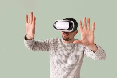 Young man using VR glasses on green background
