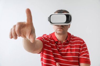 Mature man in VR glasses on light background