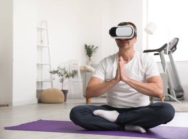 Mature man in VR glasses meditating at home