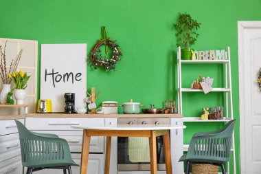 Interior of stylish kitchen with Easter wreath and dining table