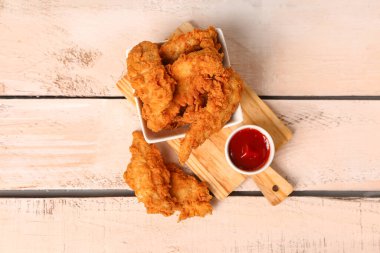 Board with tasty nuggets and sauce on light wooden background