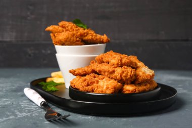 Plate with tasty nuggets on dark table