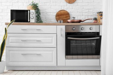 Interior of light kitchen with electric oven and white counter
