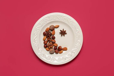 Plate, crescent with star made of nuts and anise for Ramadan on red background