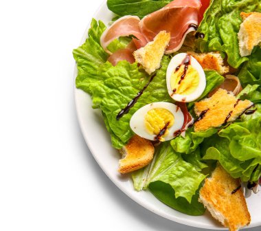 Plate of delicious salad with boiled eggs and jamon isolated on white background