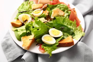Plate of delicious salad with boiled  eggs and jamon on grey background