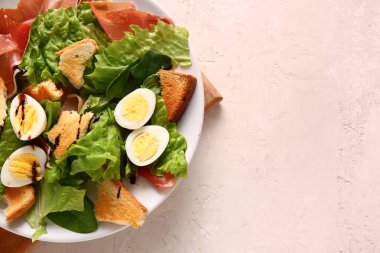 Plate of delicious salad with boiled eggs and jamon on white grunge background