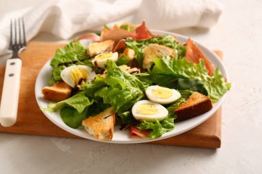 Plate of delicious salad with boiled eggs and jamon on white grunge background