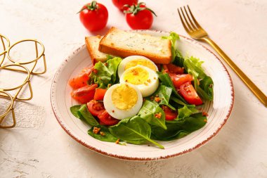 Plate of delicious salad with boiled eggs and salmon on white grunge background