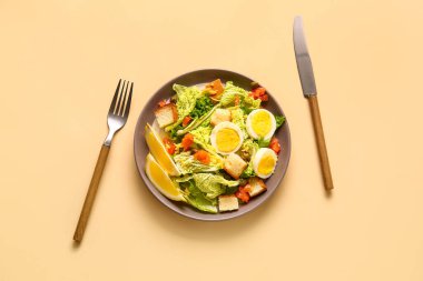 Plate of delicious salad with boiled eggs and salmon on beige background