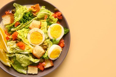 Plate of delicious salad with boiled eggs and salmon on beige background