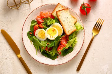 Plate of delicious salad with boiled eggs and salmon on white grunge background