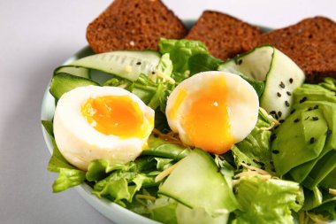 Plate of delicious salad with boiled eggs and avocado on grey background
