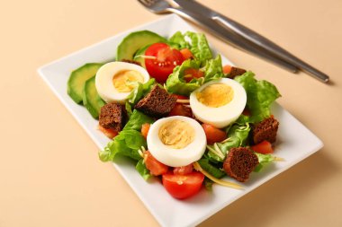 Plate of delicious salad with boiled eggs and salmon on beige background