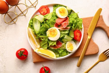 Plate of delicious salad with boiled eggs and jamon on white grunge background
