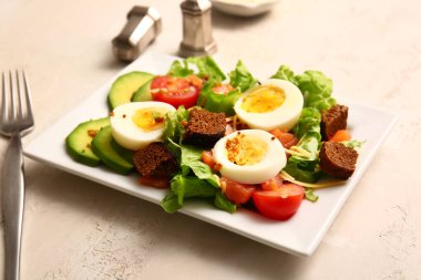 Plate of delicious salad with boiled eggs and salmon on white grunge background