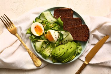 Plate of delicious salad with boiled eggs and avocado on white grunge background