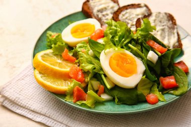 Plate of delicious salad with boiled eggs and salmon on white grunge background
