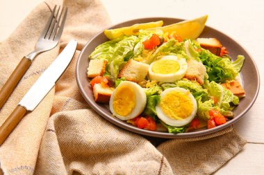 Plate of delicious salad with boiled eggs and salmon on white wooden background