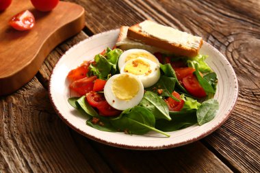 Plate of delicious salad with boiled eggs and salmon on brown wooden background