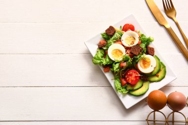 Plate of delicious salad with boiled eggs and salmon on white wooden background