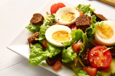 Plate of delicious salad with boiled eggs and salmon on white wooden background