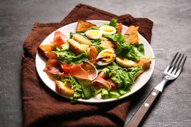 Plate of delicious salad with boiled eggs and jamon on black grunge background
