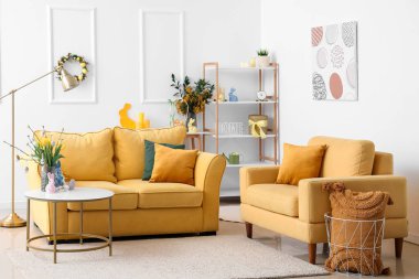 Interior of living room with yellow sofa, flowers and Easter eggs
