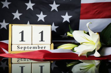 Calendar with date of National Day of Prayer and Remembrance for the Victims of the Terrorist Attacks, lilies, USA flag on glass table