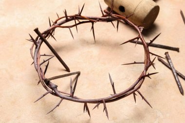 Crown of thorns with nails and mallet on beige background, closeup. Good Friday concept