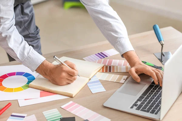 Male painter using laptop at table in room, closeup