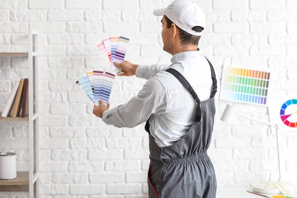 Male painter with color palettes near white brick wall