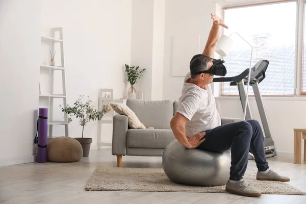Mature man in VR glasses training at home
