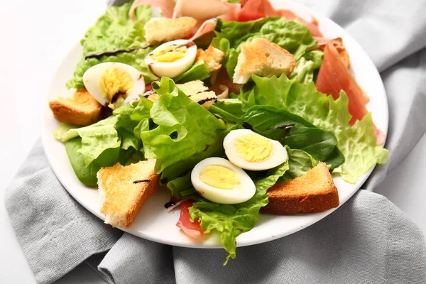 Plate of delicious salad with boiled  eggs and jamon on grey background