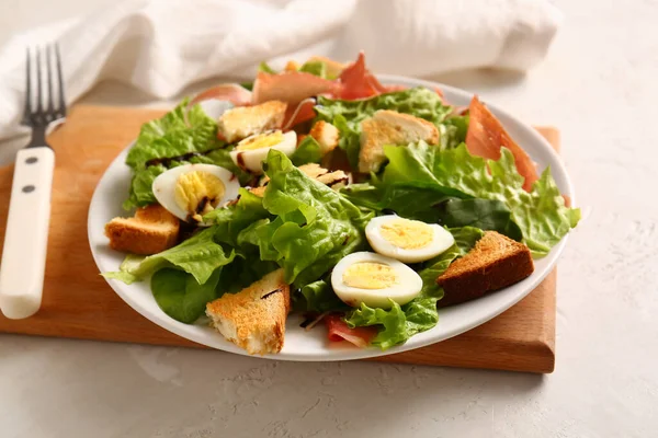 Plate of delicious salad with boiled eggs and jamon on white grunge background