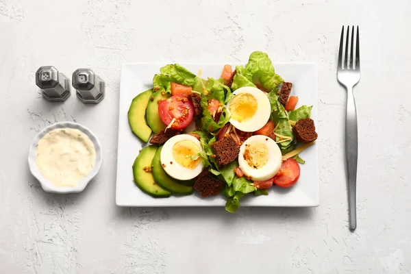 Plate of delicious salad with boiled eggs and salmon on white grunge background